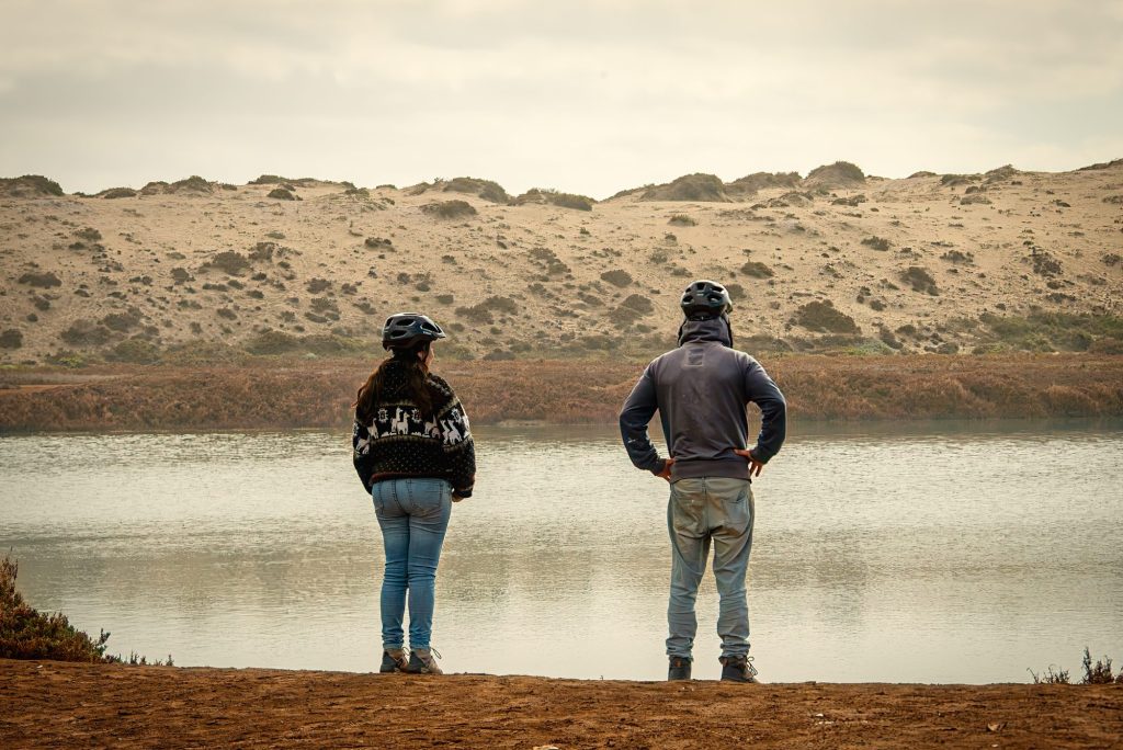Dos visitantes contemplando la laguna del Humedal La Boca y las dunas